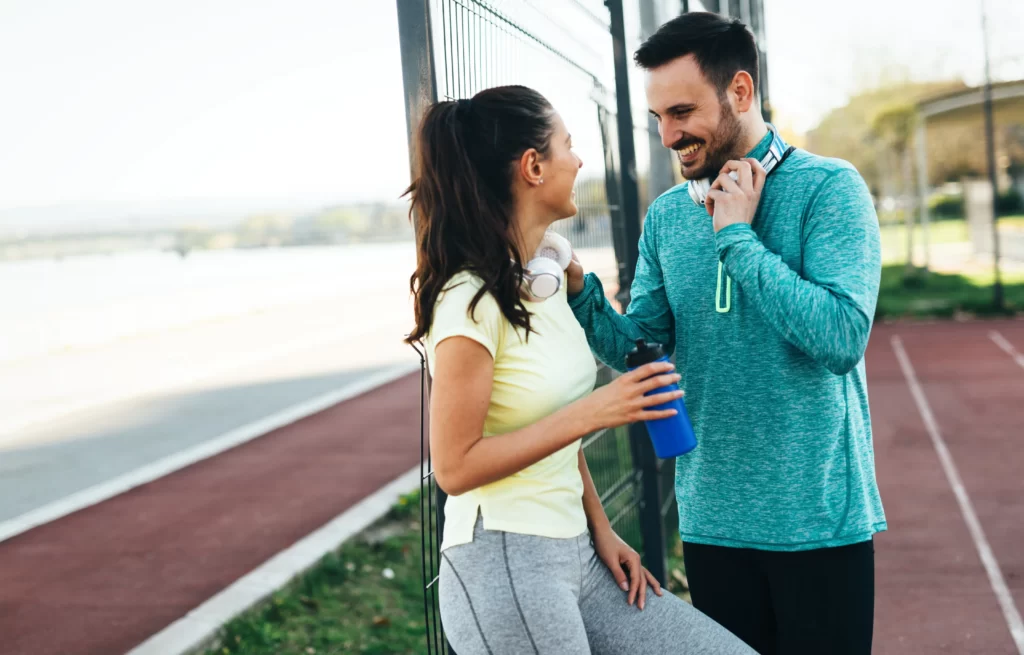 fit couple smiling post workout on running track utc